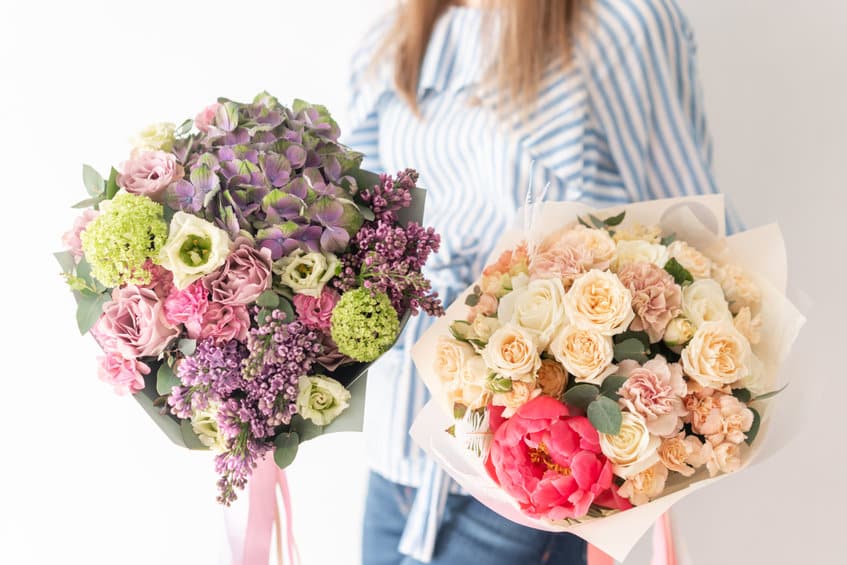 two beautiful bouquets of mixed flowers in womans hands. the work of the florist at a flower shop. delicate pastel color. fresh cut flower.